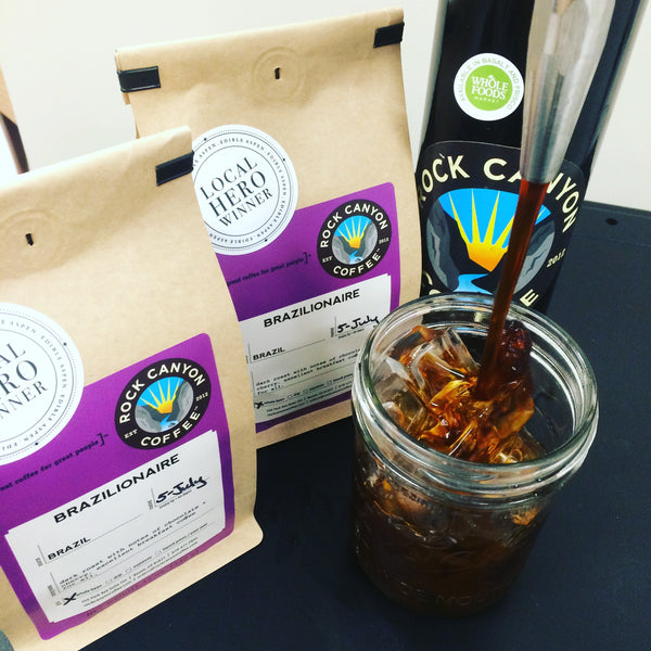 Nitro Cold Brew Coffee over ice next to craft coffee bags