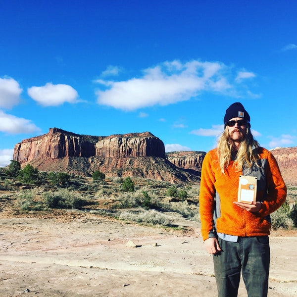 John posing with decaf bag in Indian Creek Utah with sandstone landscape in background