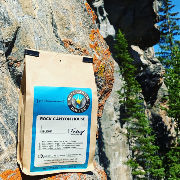 Bag of Rock Canyon Coffee sitting on rock with pine trees in the background.
